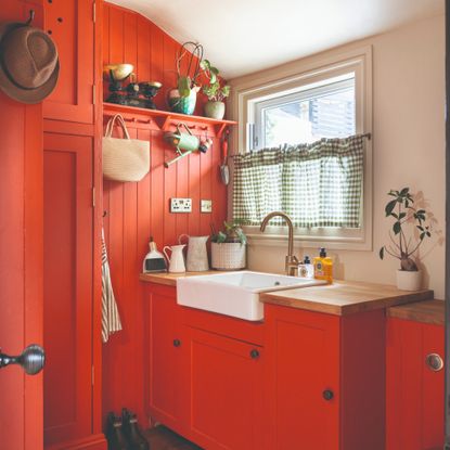 A panelled boot room painted in a bright orange shade paired with a softer pink on one wall and the ceiling