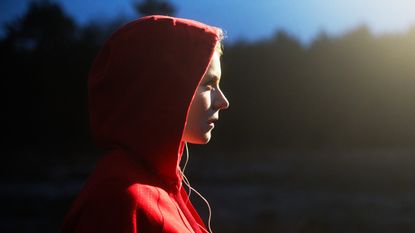 Young woman in hooded top listening to music. - stock photo