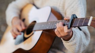 Woman playing acoustic guitar with a capo