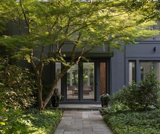 exterior of gray contemporary house with trees and park around