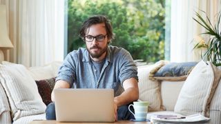 Man sitting on sofa and using laptop at home