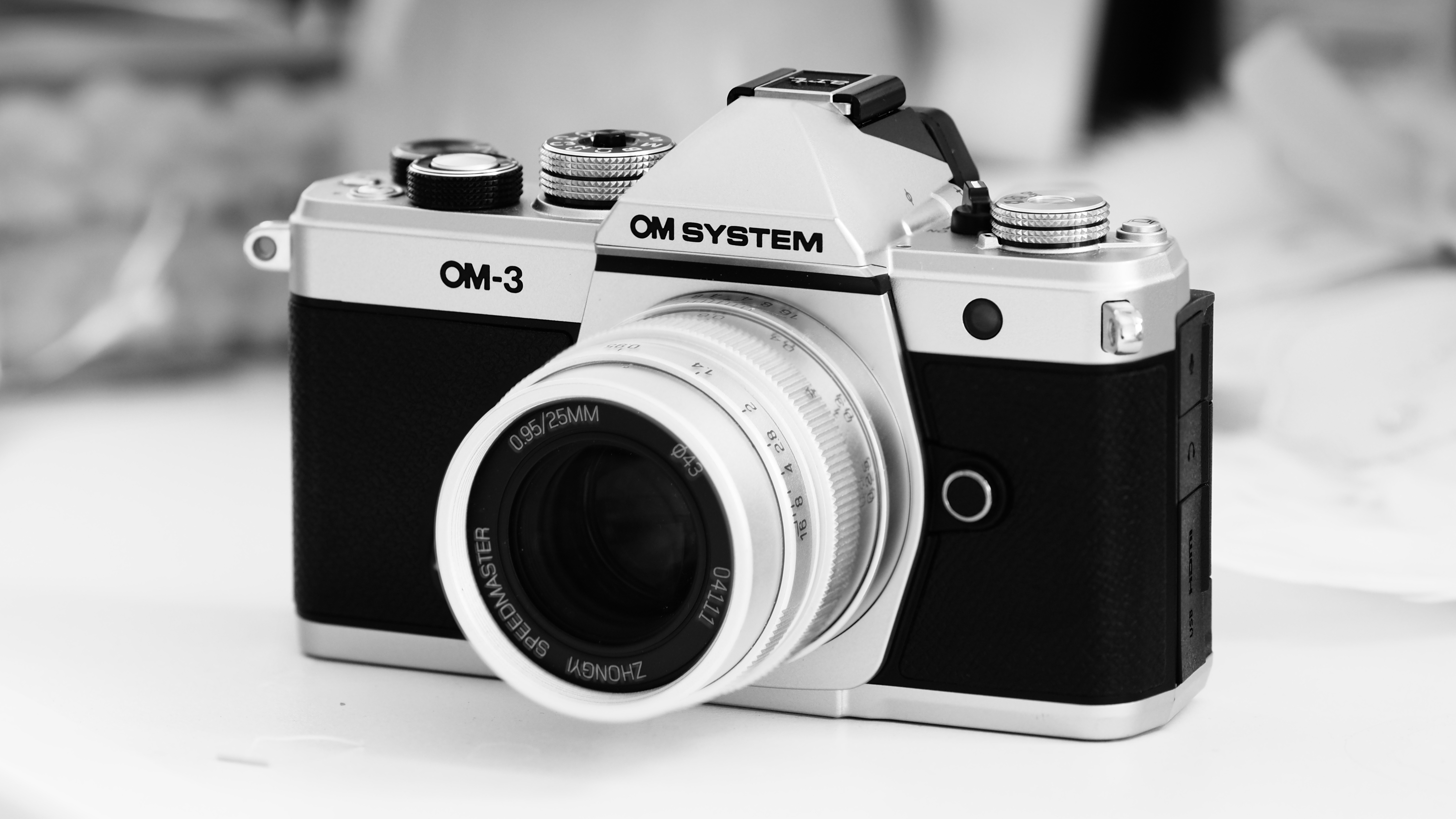Black-and-white photo of the OM System OM-3 with the Mitakon Speedmaster 50mm f/0.95
