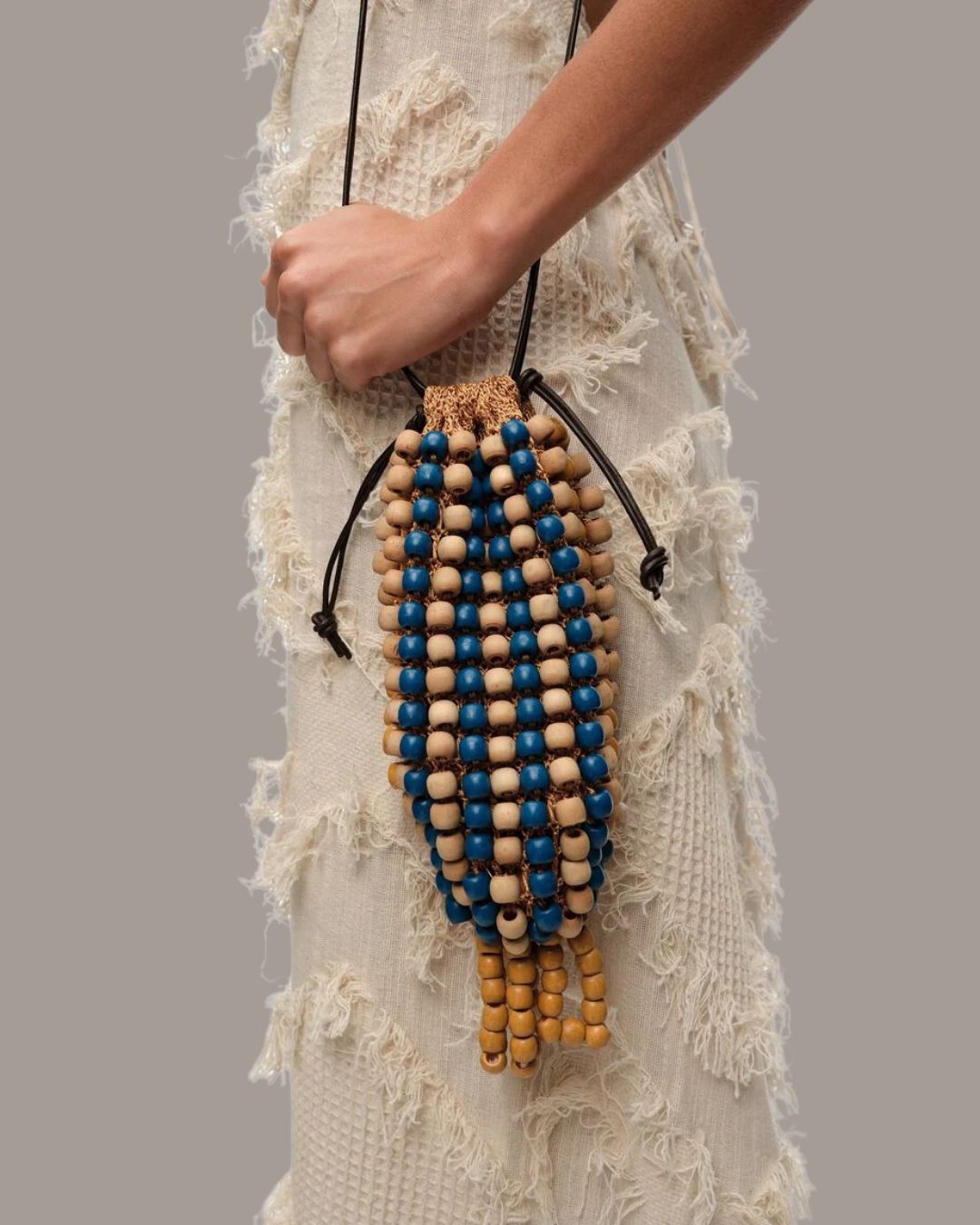 BIMBA Y LOLA Blue Crochet Mini Bag worn by a model in a beige dress against dark beige background.