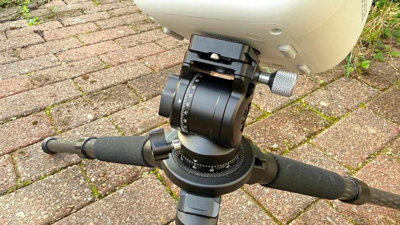 The ZWO Seestar TH10 fluid head attached to the ZWO Seestar S50 Pro and tripod with a brick floor in the background.