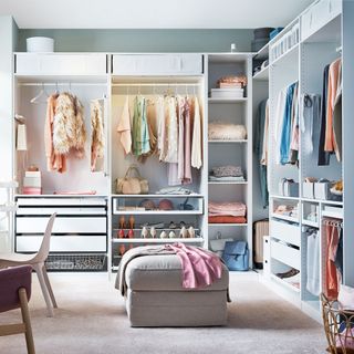 Modular wardrobe comprising of several hanging rails and shelves, in a white bedroom