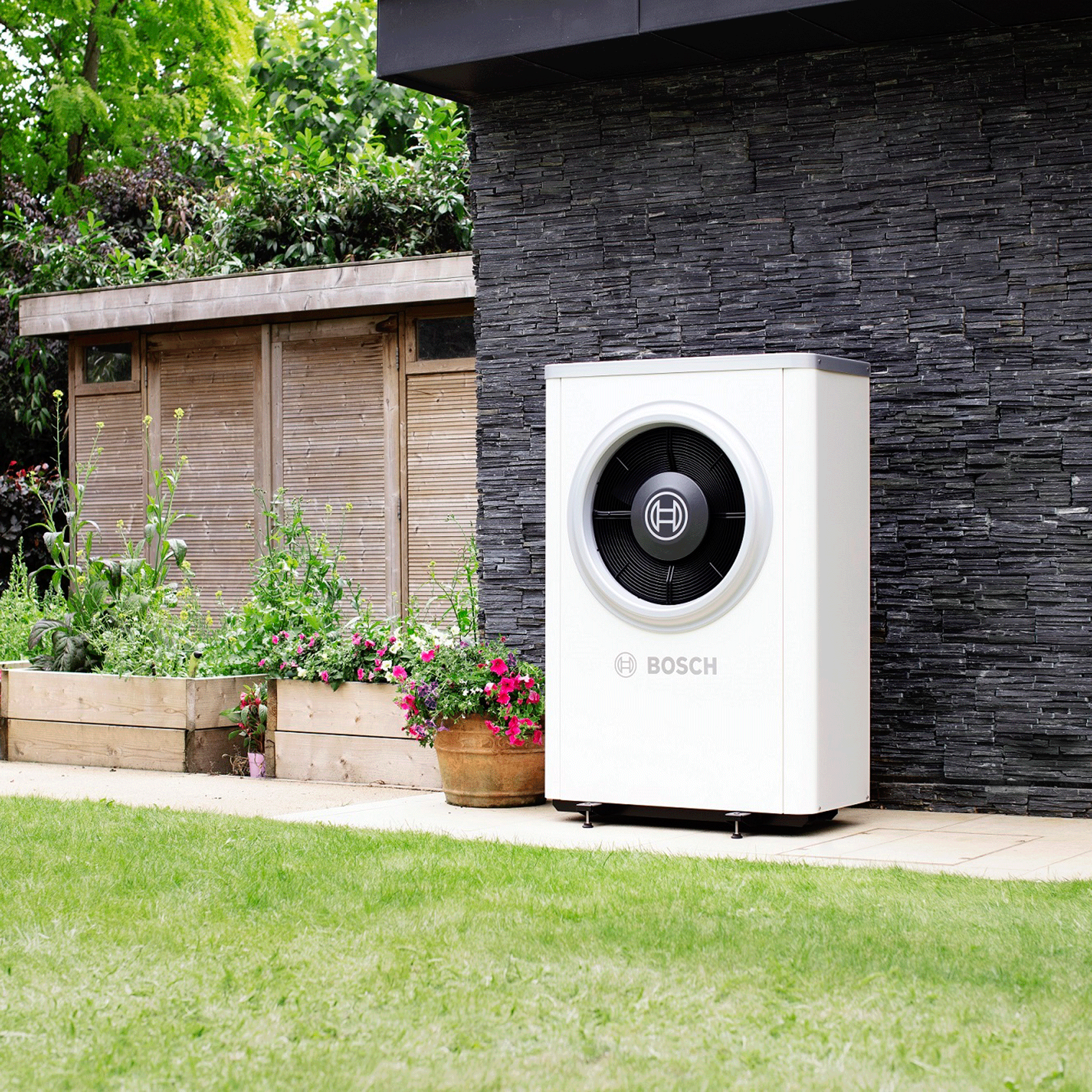 Heat pump outside black building with green lawn