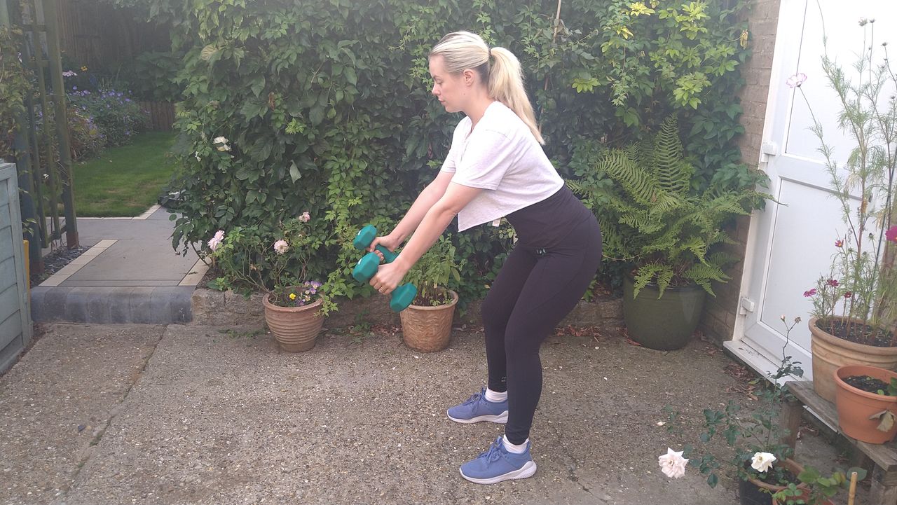Stacey Carter performs dumbbell row in back yard