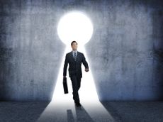 Investor carrying a briefcase walking through an illuminated keyhole