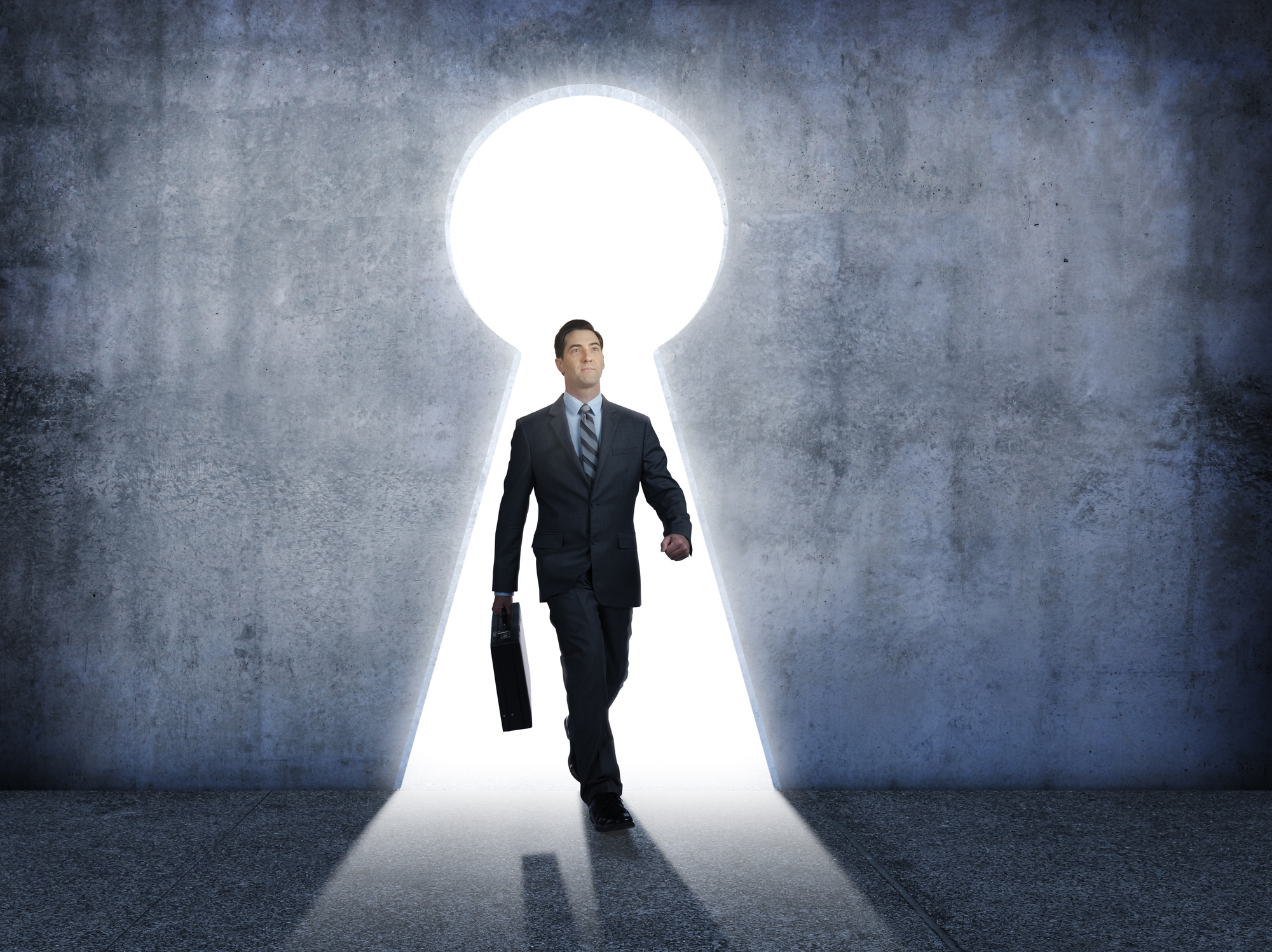Investor carrying a briefcase walking through an illuminated keyhole