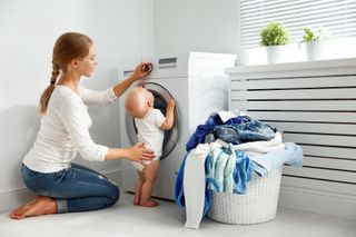 Mom putting laundry in washing machine.