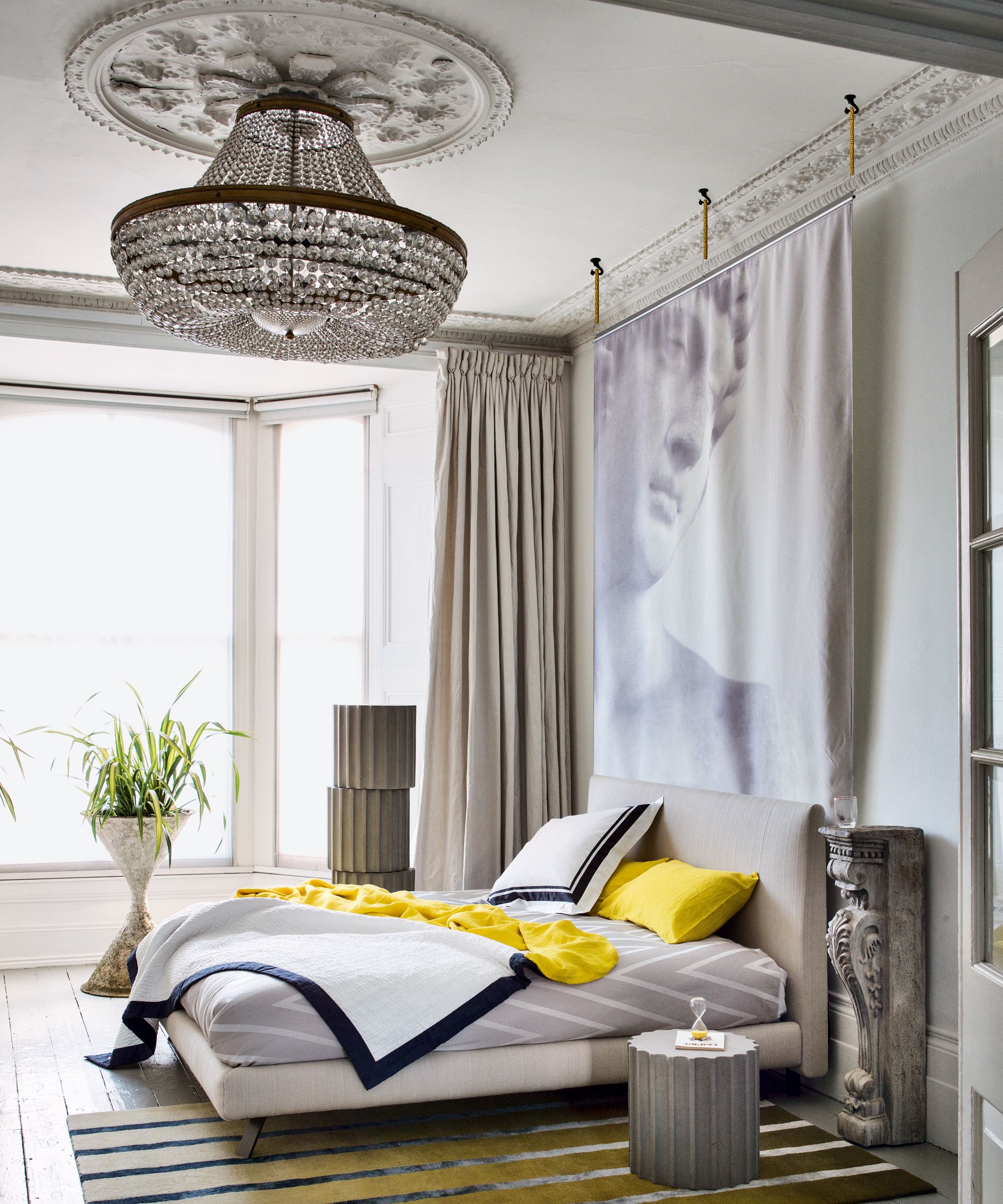 A bedroom with a large empire chandelier and contemporary wall artwork