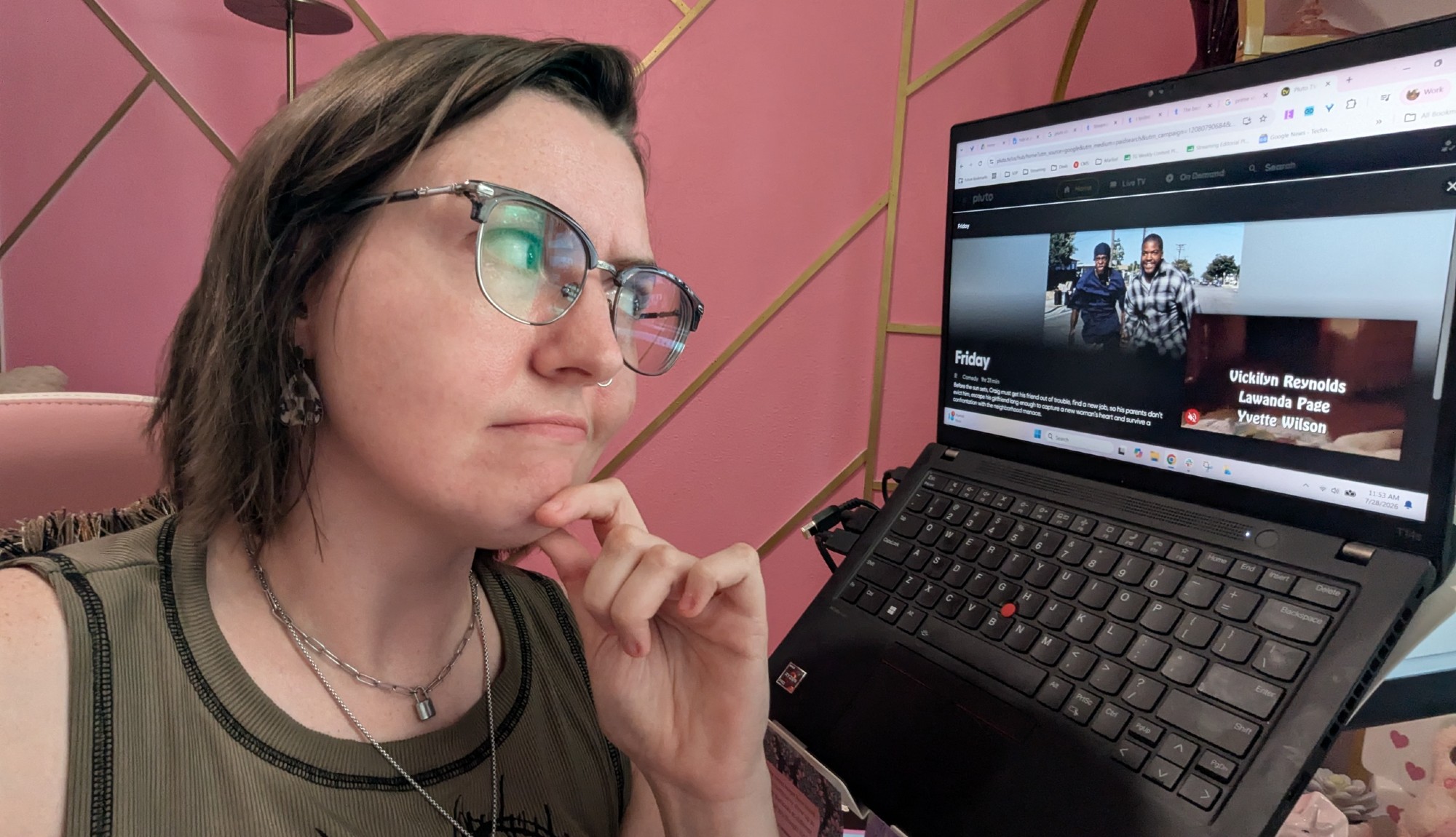 A person with a look of concentration staring at a laptop screen with Pluto TV open and Friday playing