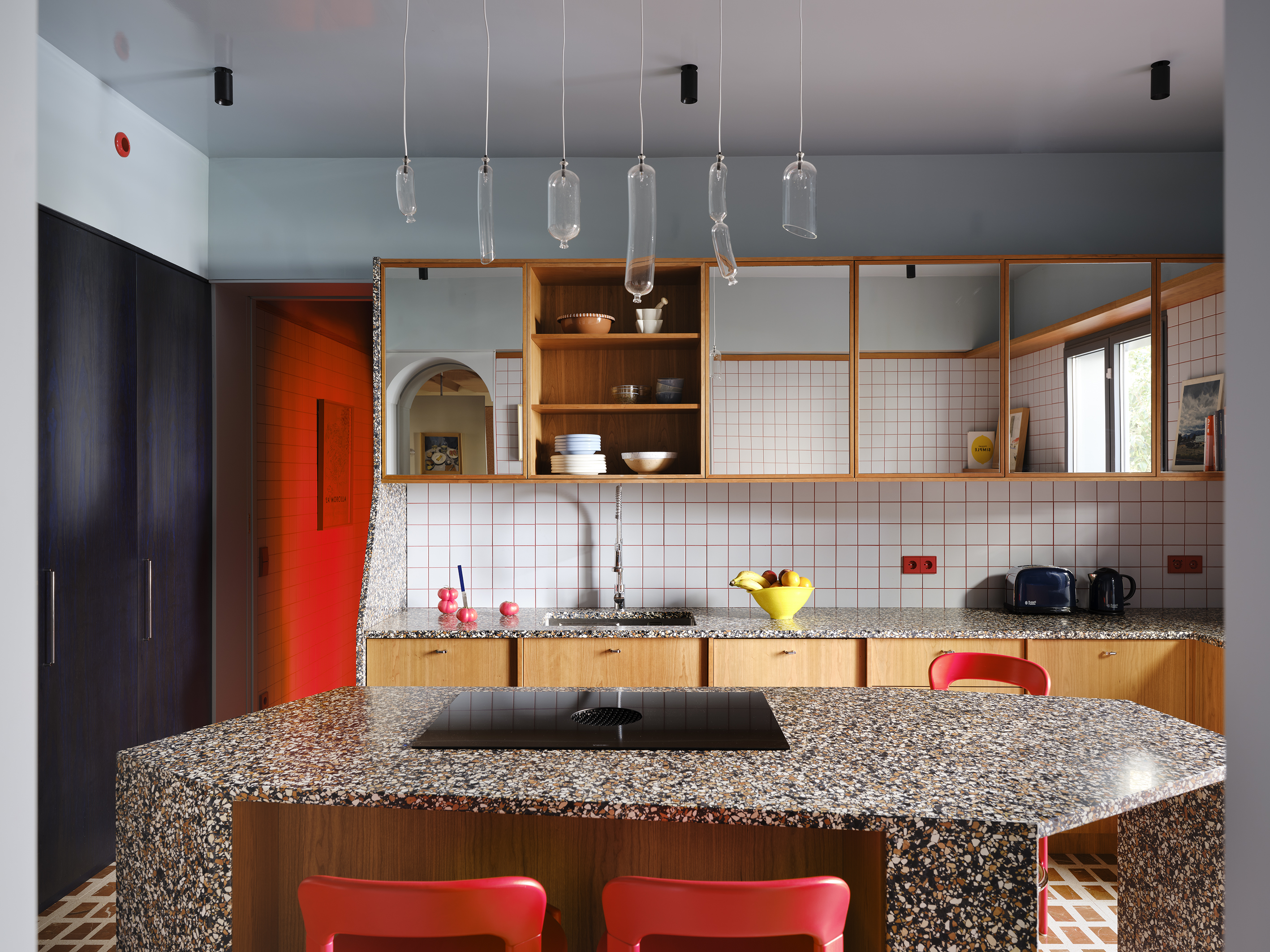 a modern kitchen design with terrazzo worktops, white splashbacks and orange grout