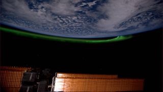 A photo of a green aurora reaching up in an arc on an upside-down earthing