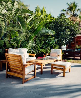 A wooden garden furniture set in a tropical themed garden