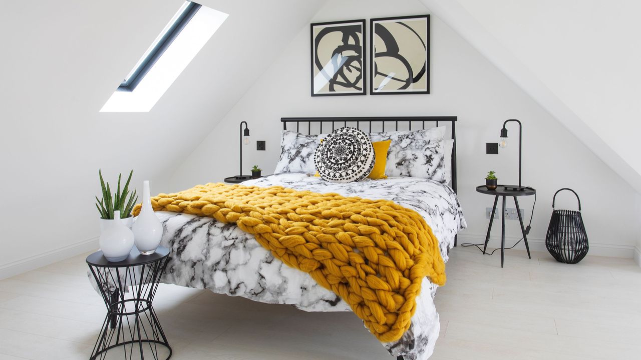 Monochrome loft bedroom with rooflight and mustard yellow throw blanket on the bed