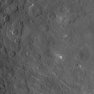 This image of the dwarf planet Ceres, taken by NASA's Dawn spacecraft, features a large, steep-sided mountain and several intriguing bright spots.