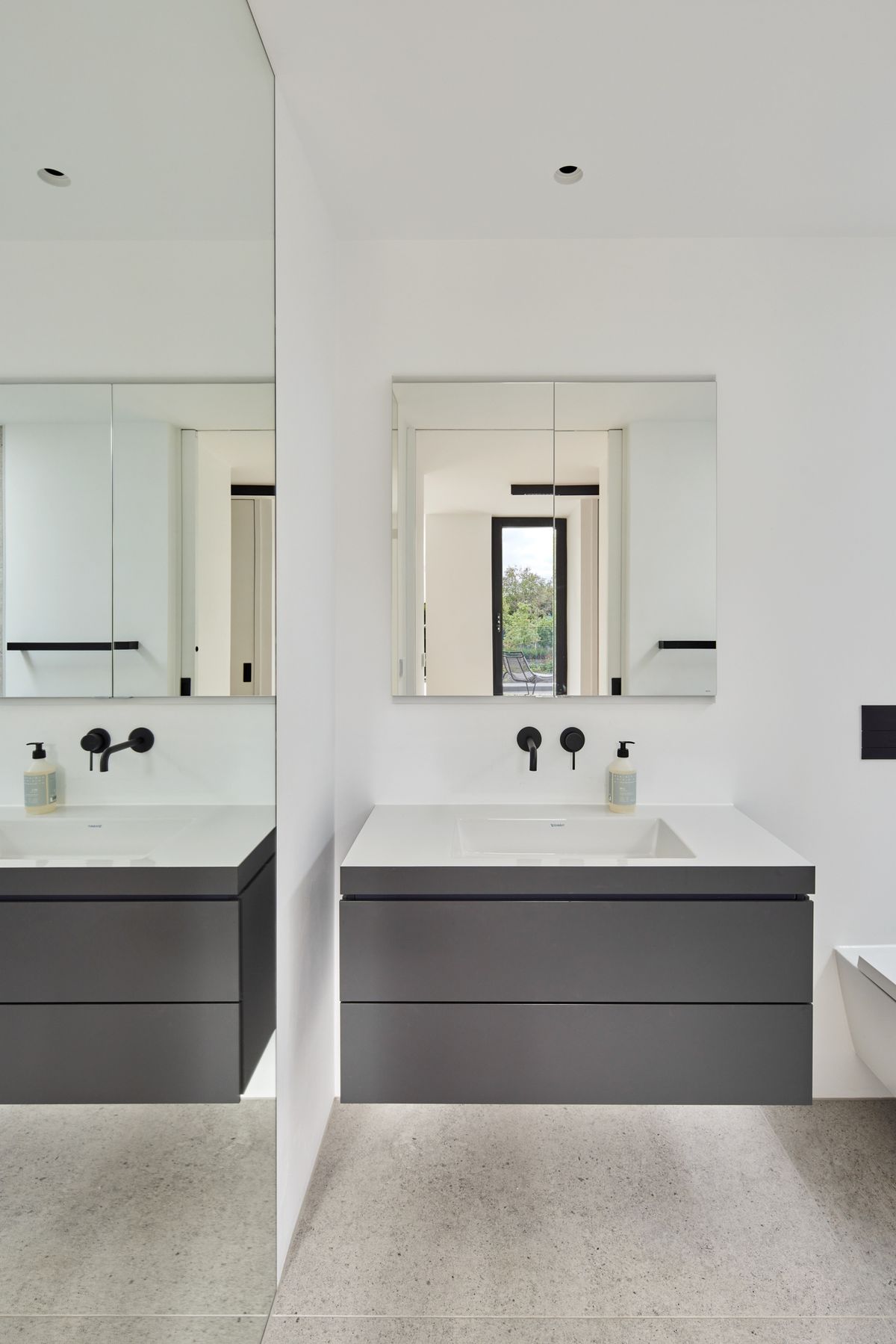 A white minimalist bathroom with a wall hung vanity unit and mirror
