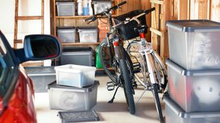plastic boxes stacked in garage with bikes and wooden shelving
