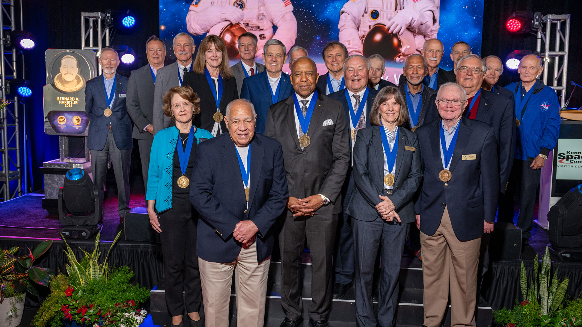 a group of men and women in business suits pose together on a stage