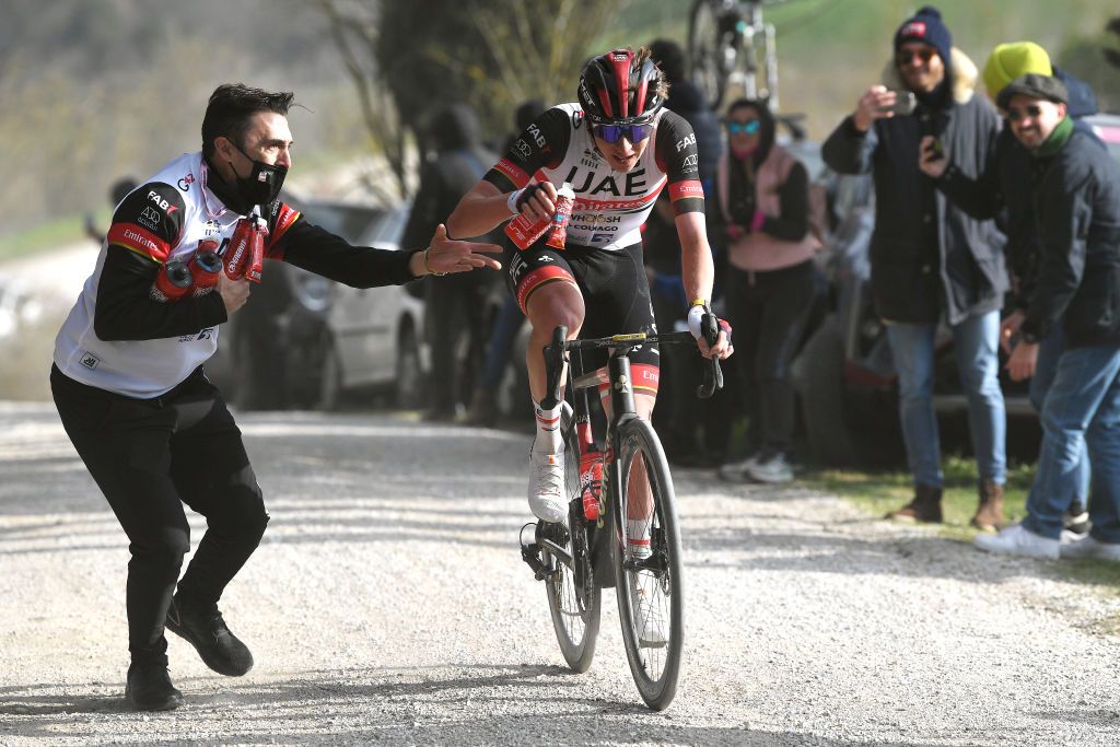 SIENA ITALY MARCH 05 Tadej Pogacar of Slovenia and UAE Team Emirates picks food from a team Soigneur in the attack during the Eroica 16th Strade Bianche 2022 Mens Elite a 184km one day race from Siena to Siena Piazza del Campo 321m StradeBianche WorldTour on March 05 2022 in Siena Italy Photo by Tim de WaeleGetty Images