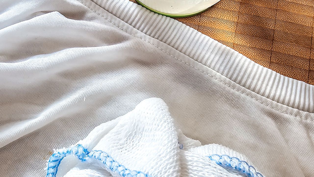 A white t-shirt with a white cloth on top of it on top of a wooden chopping board