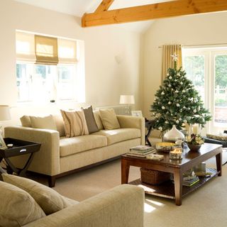 living room with cream colour sofa with cushion white wall and christmas tree