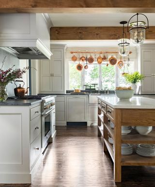 Rustic white kitchen with wooden island and hanging copper pots