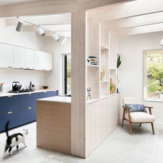 blue and white kitchen with timber divider and an armchair beside the window