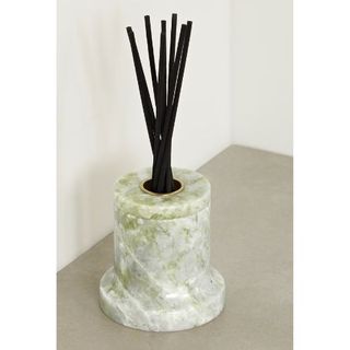 A small green marble pot with black diffuser sticks