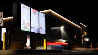 A fast-food drive-thru menu powered by PDG digital signage solutions at night.