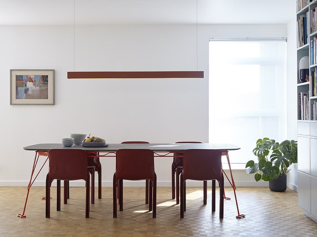 Terracotta pendant light suspended over a dining table with red chairs