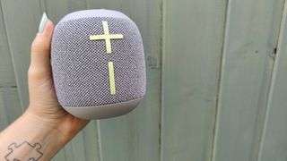 Ultimate Ears Wonderboom 3 speaker in grey held up against blue shed