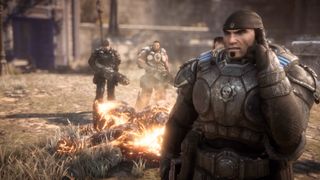 Marcus standing in front of a burning corpse in Gears of War: Reloaded
