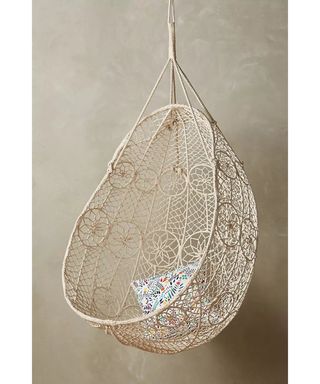 A cream colored macrame hanging egg chair