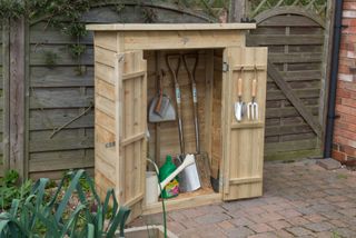 wooden storage unit on a patio filled with tools