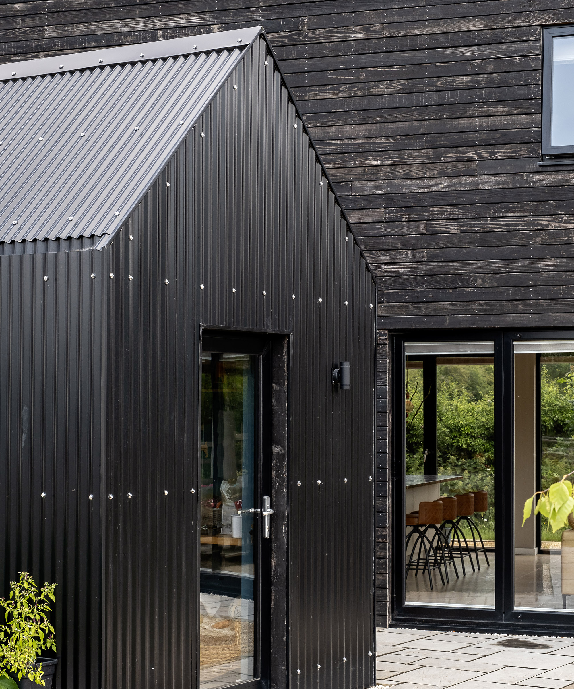 A metal clad front door entranceway attached to a main building of a self build