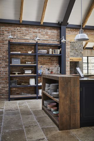 open plan kitchen with open shelving unit, stone floor, exposed brick, kitchen island