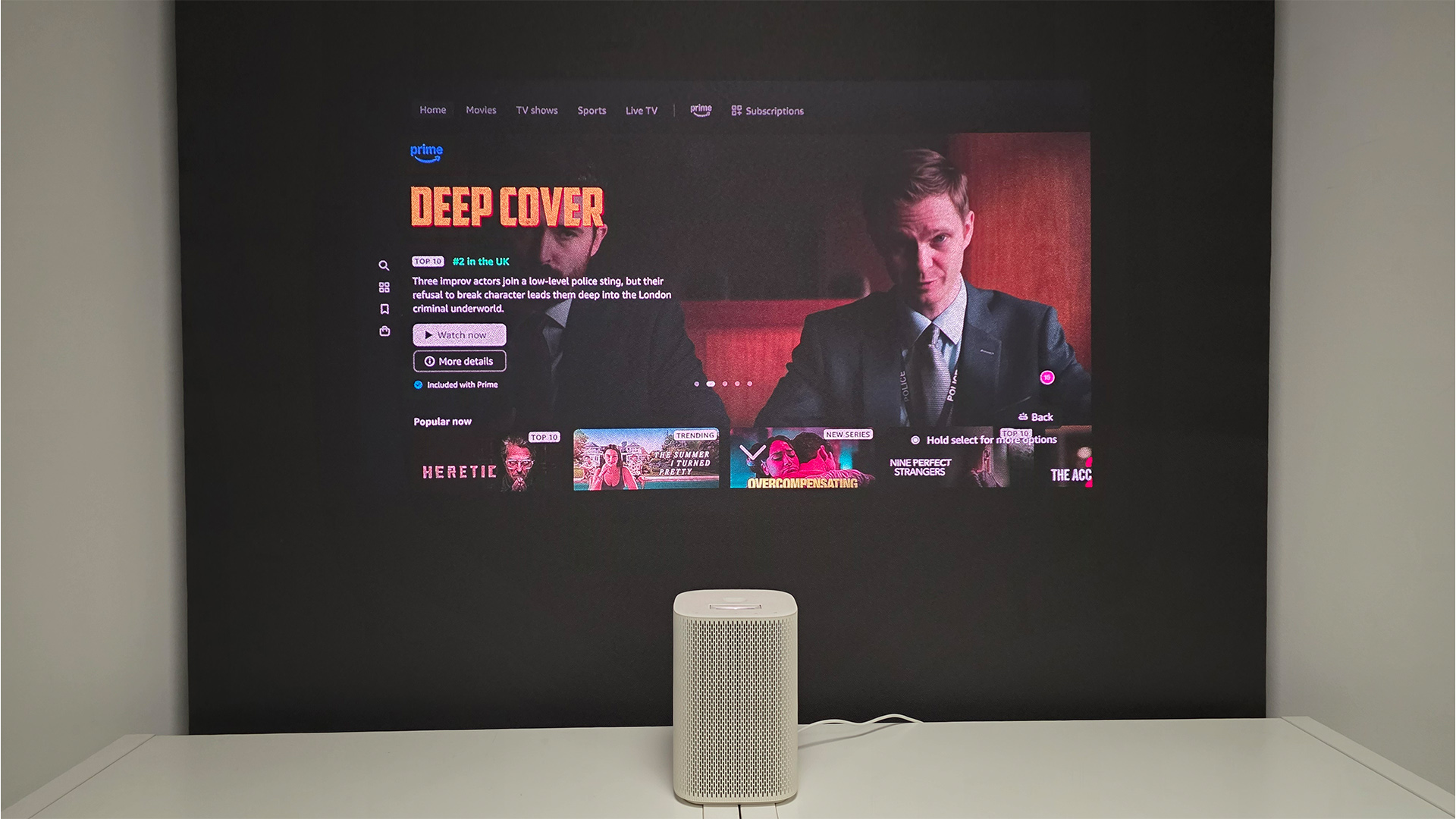 Samsung The Premiere 5 ultra short throw projector in front of screen showing Deep Cover
