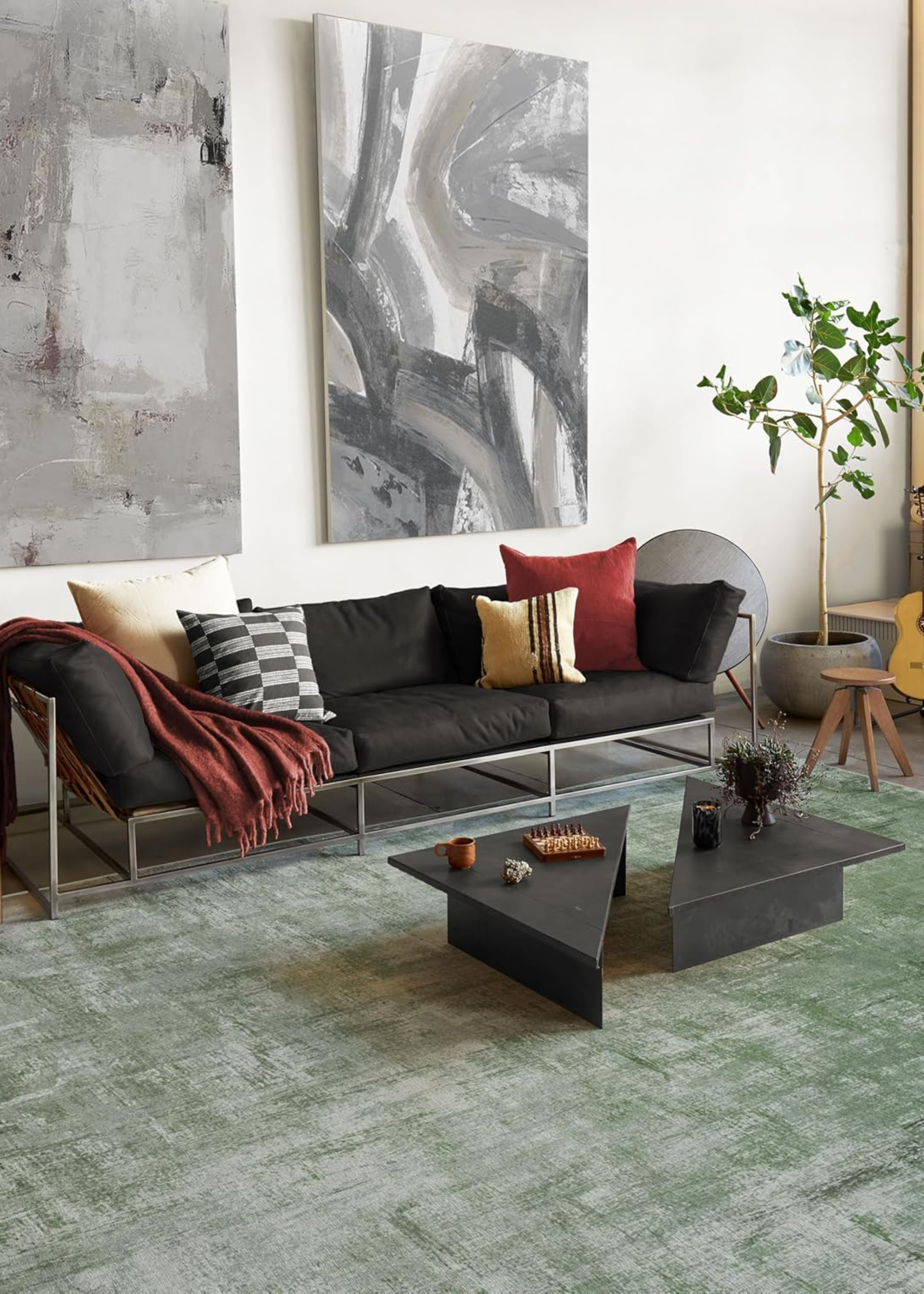 olive green ruggable rug in a living room with a black sofa with silver metal frame and abstract split black coffee table with two large pieces of artwork on the white wall behind