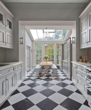 orangery kitchen extension at end of narrow kitchen with white units and black and white chequered tiled floor