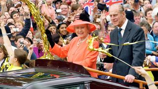 Queen Elizabeth II and Prince Phillip the Duke of Edinburgh ride along the Mall in an open top car