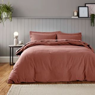 A bed with terracotta bedding