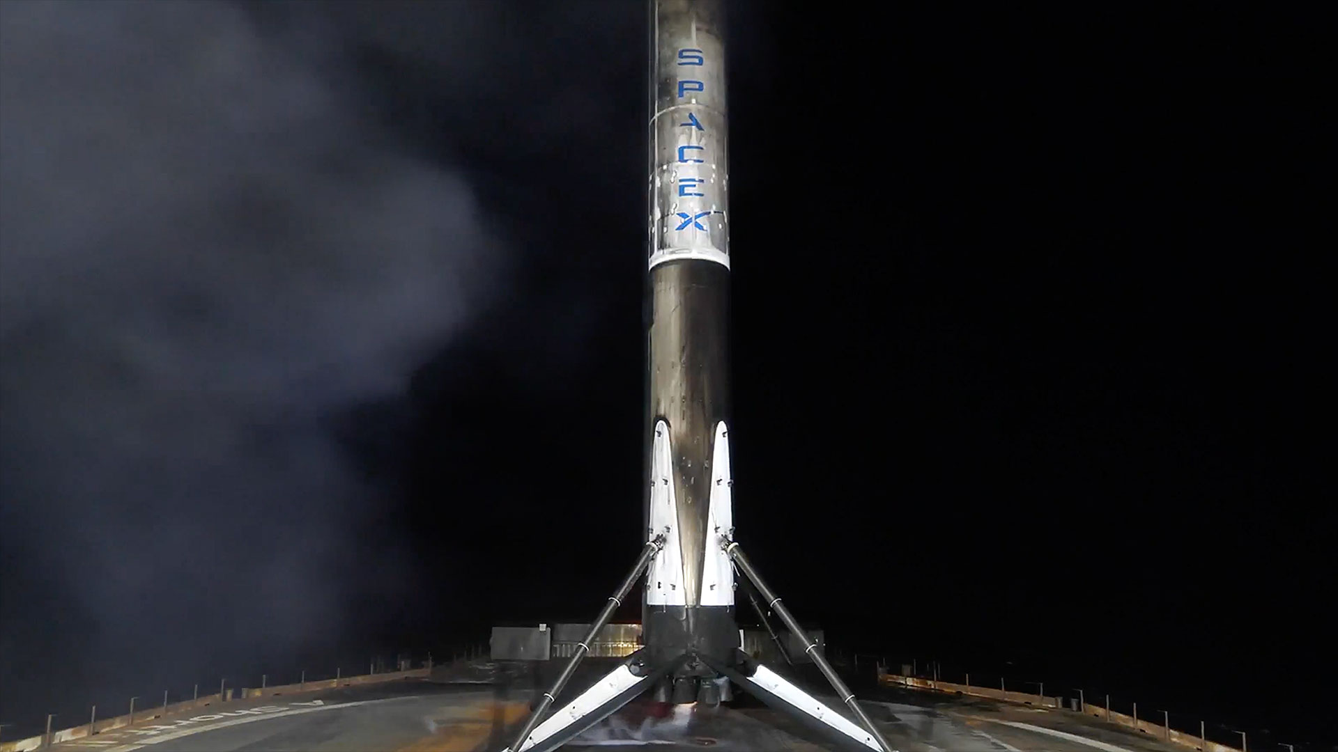 the first stage of white booster rocket stands on its four landing legs atop a sea-based droneship after launching to space