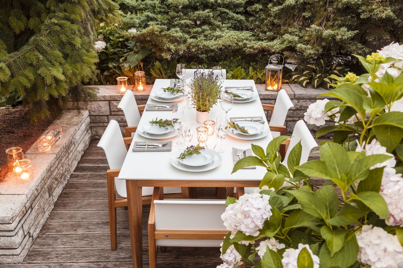 outdoor dining table at dusk lit by candles and lanterns