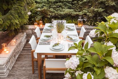outdoor dining table at dusk lit by candles and lanterns