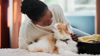 Women lying on bed petting her cat who gazes up at her lovingly