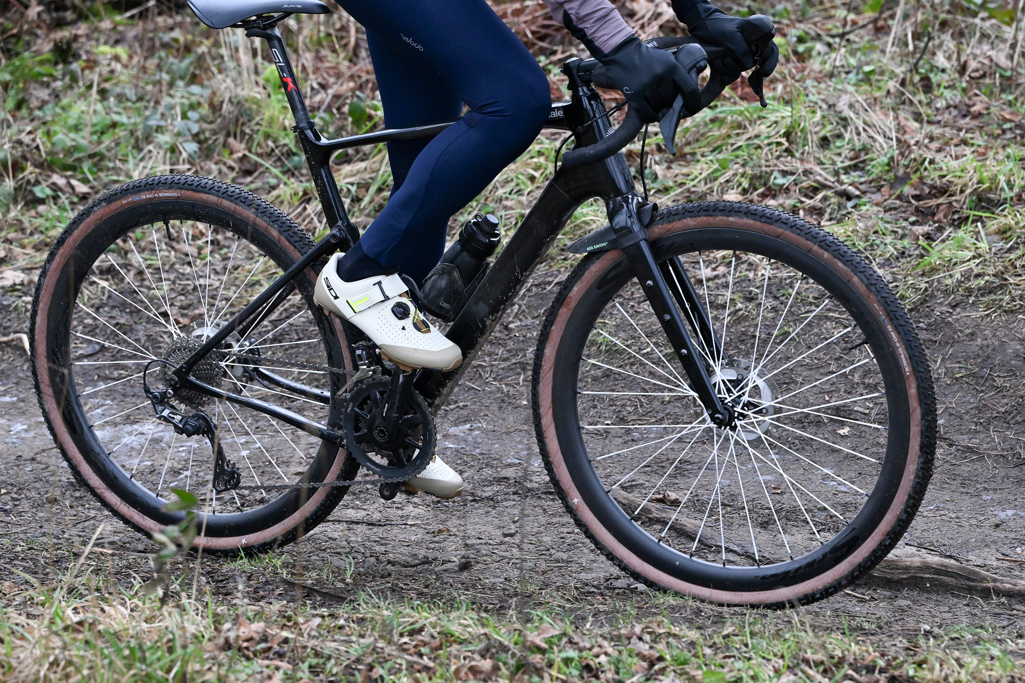 side shot of a black gravel bike with G-One RX Pro Gravel tyres on a dirt trail