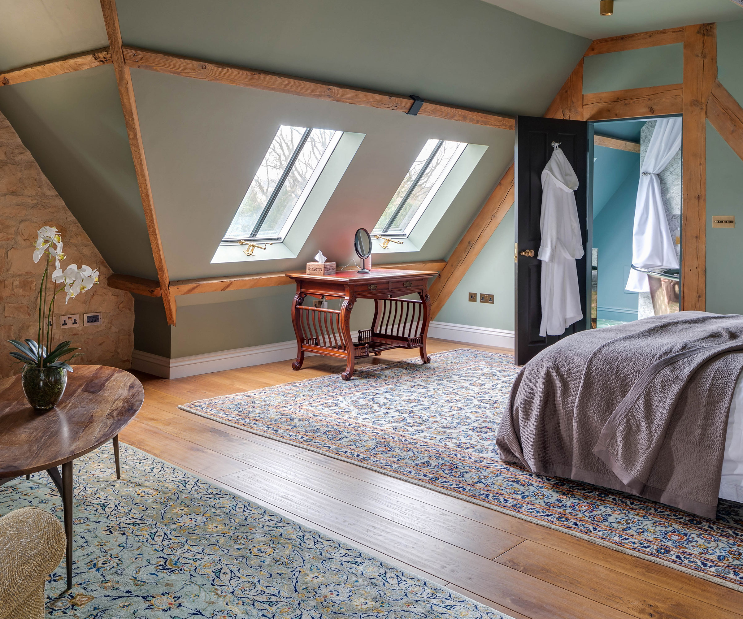 bedroom in a loft space with exposed timber rafters and two conservation-style rooflights