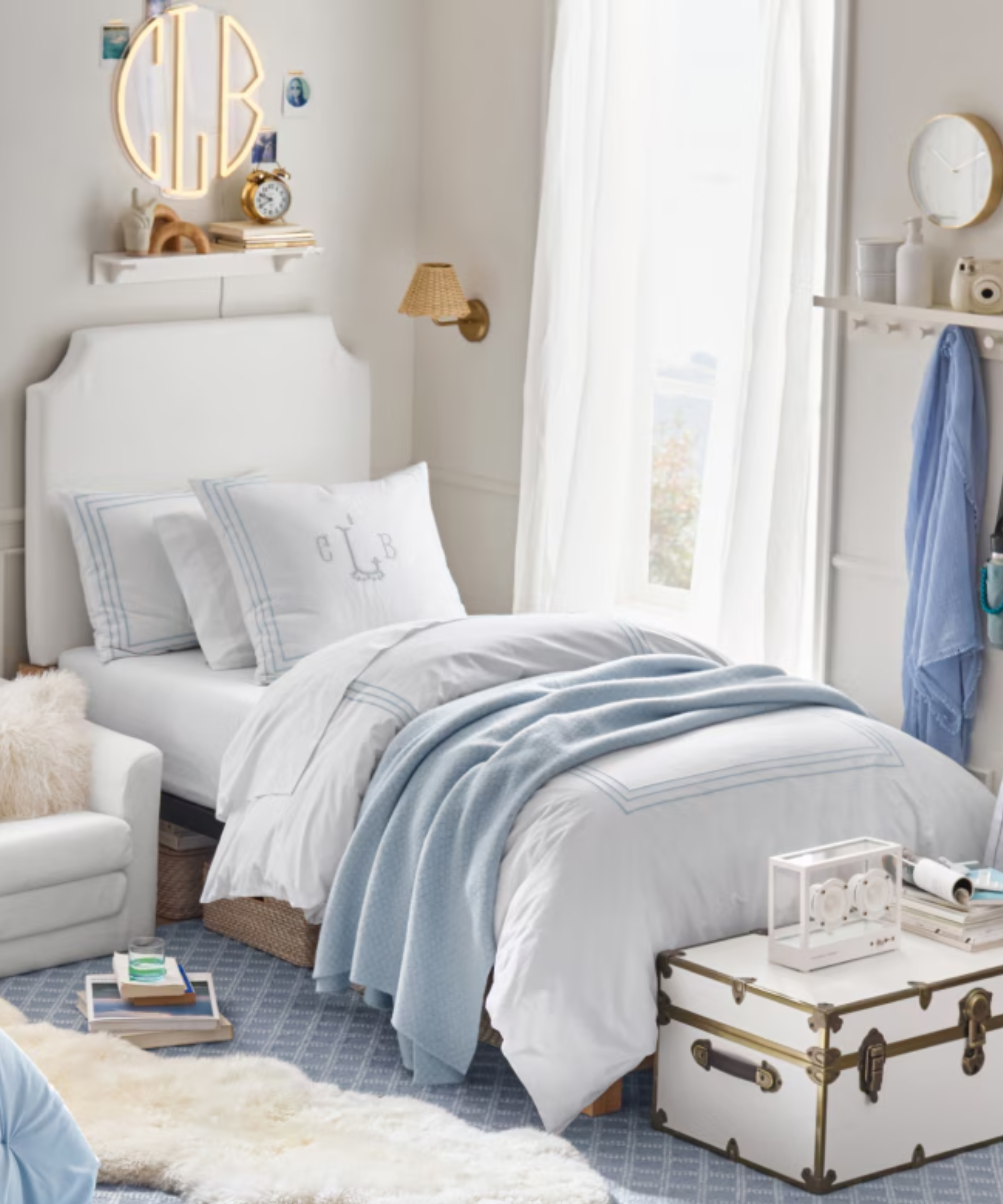 a dorm room with white and blue bedding and a window with curtains